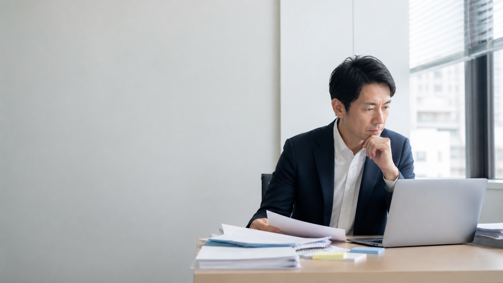 情報整理に悩み、資料を確認する企業担当者